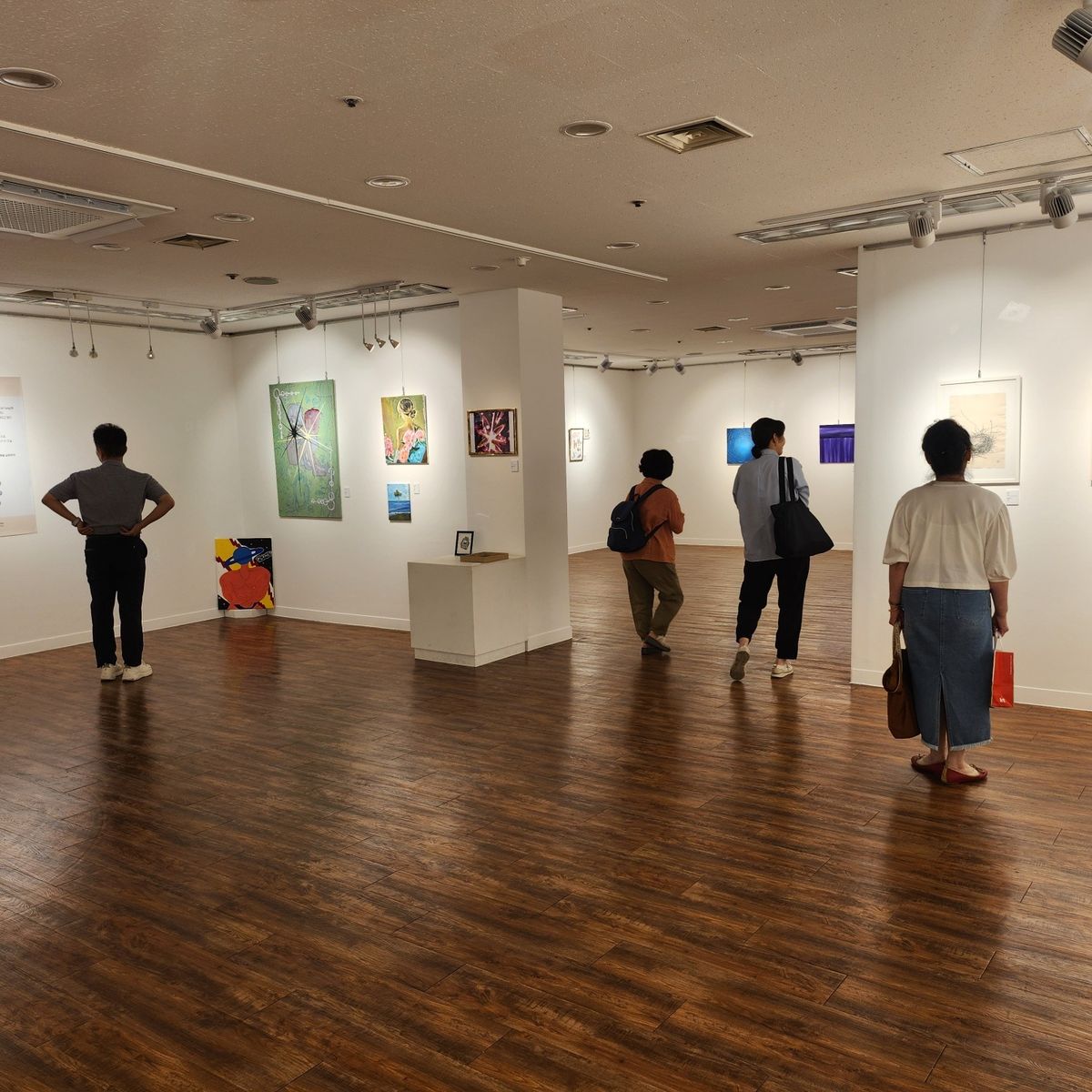 MBTI 展 전시장에서 작품을 보는 관람객들의 뒷모습